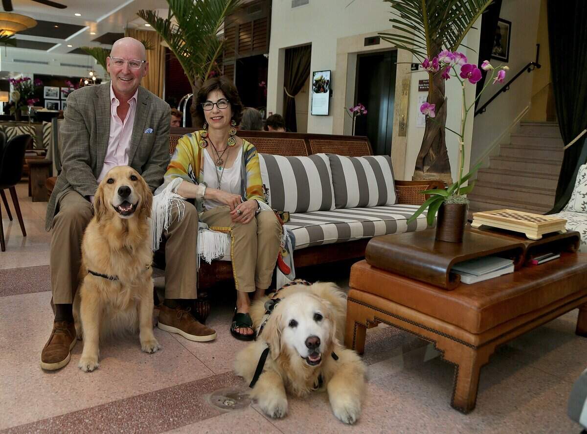 In this file photo, The Betsy hotel owners Jonathan Plutznik Lesley Goldwasserin posed with their golden retrievers, Betsy and Kate, in the lobby of their Miami Beach hotel.